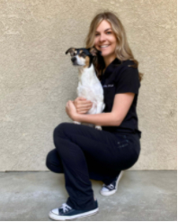 A woman kneeling down holding a small dog.