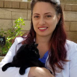 A woman holding a black cat in her arms.