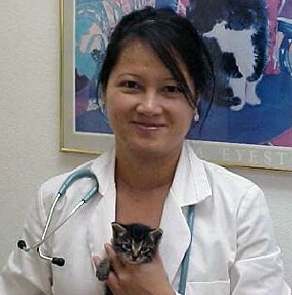 A woman holding a cat in her hand.
