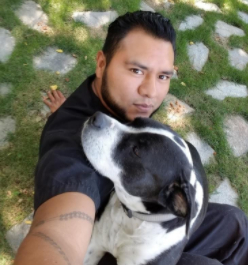 A man and his dog are sitting on the ground.