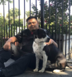 A man sitting on the ground with his dog.