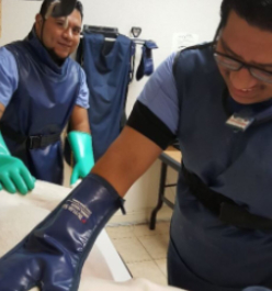 Two men in blue scrubs and green gloves.